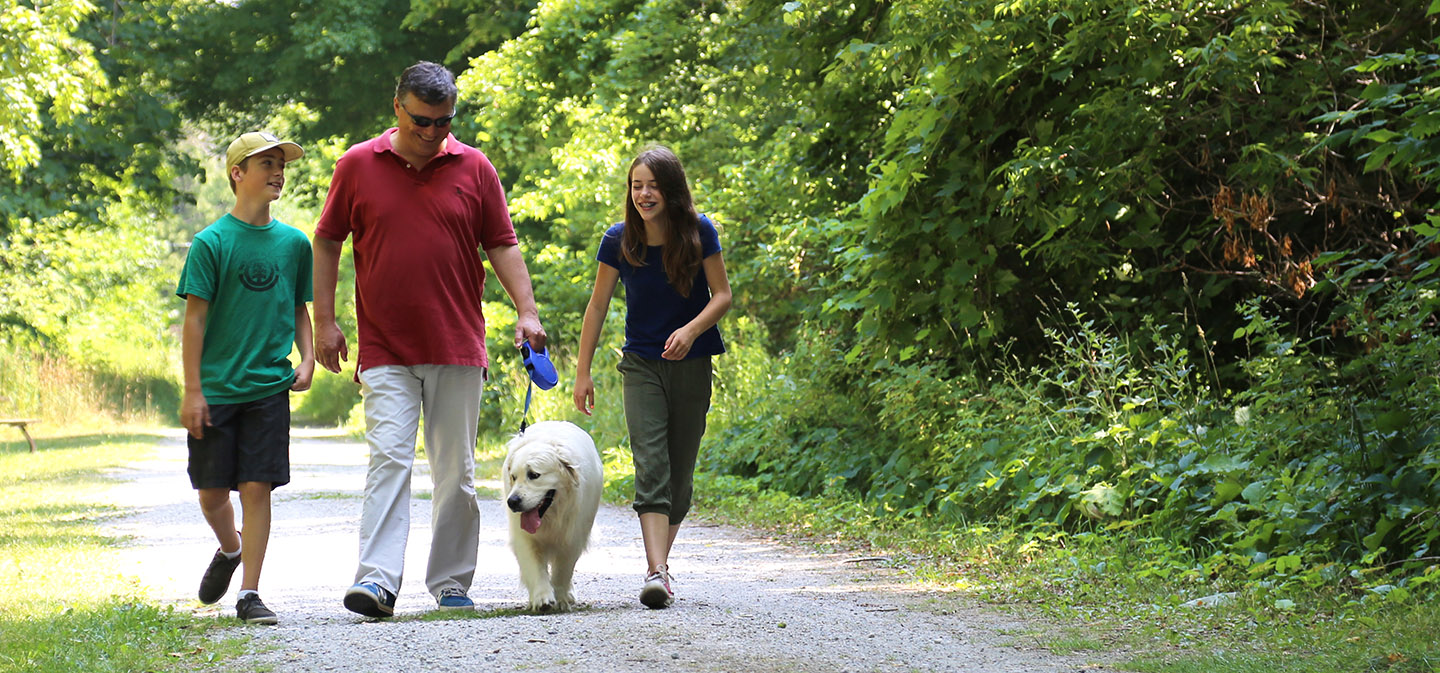 family taking dog for a walk on trail at Kortright Centre for Conservation