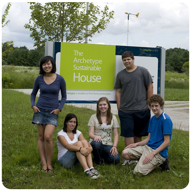 students pose with Archetype Sustainable House sign