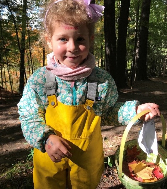 student at The Nature School uses a basket to collect colourful fall leaves