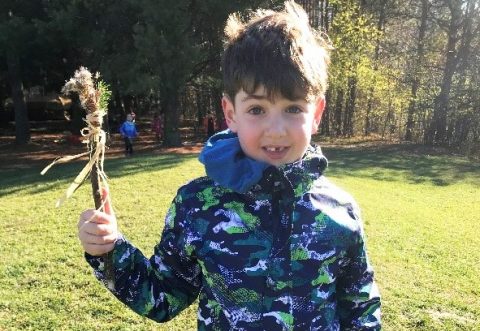 student at The Nature School at Kortright Centre proudly holds up a stick