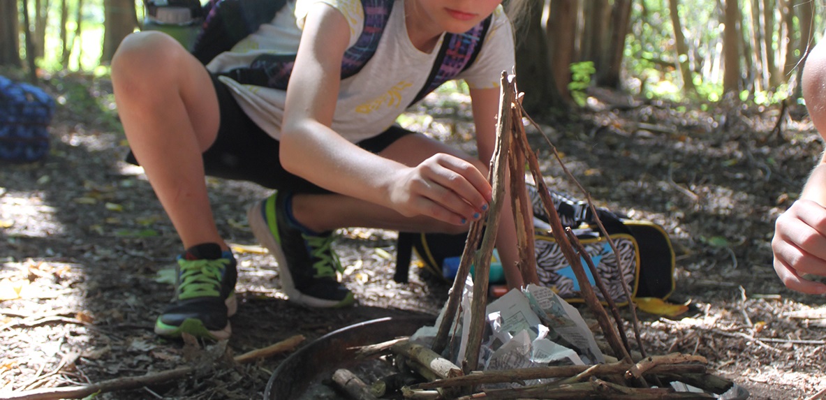 young visitor to Kortright Centre learns to build a fire as part of the wilderness survival skills program